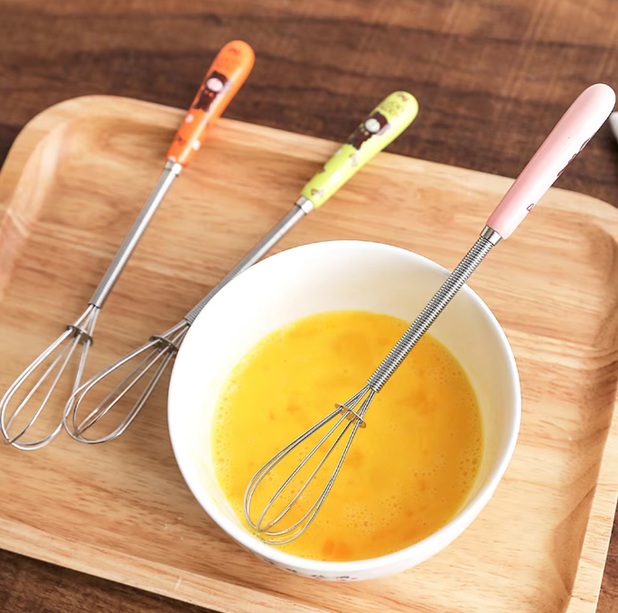 Mini stainless steel egg beater with ceramic handle, perfect for whisking eggs, frothing coffee, and mixing kitchen ingredients.