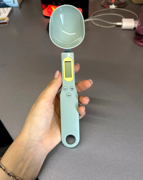 High-precision digital weighing spoon with LCD display, measuring various baking ingredients accurately for perfect recipes.